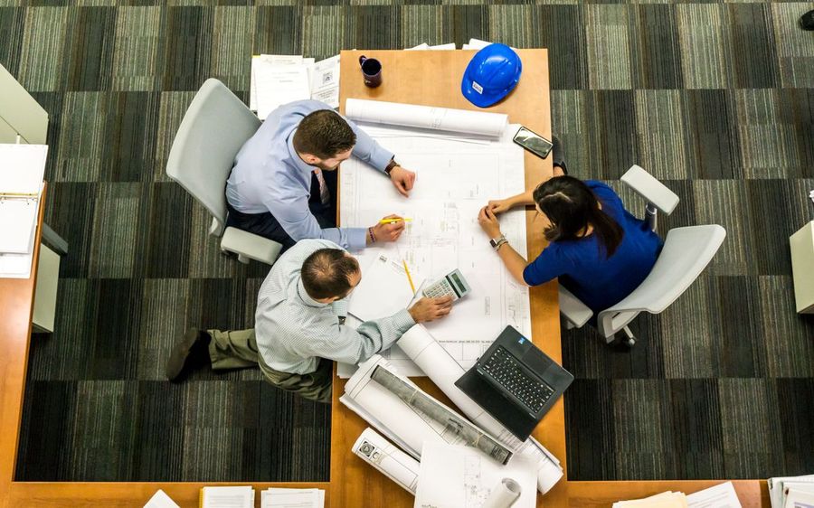 Inventors reviewing plans together around a workbench
